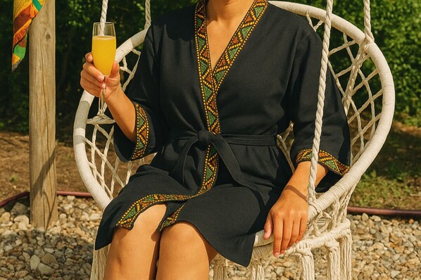 A person sitting on a wicker swing chair outdoors. - African Hut  (Tulbaghweg)