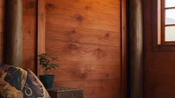 Une pièce en bois avec un lit, un oreiller, une plante en pot et une fenêtre.