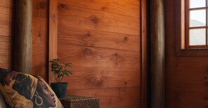 Une pièce en bois avec un lit, un oreiller, une plante en pot et une fenêtre.