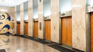 Un hall d’hôtel doté d’un sol en marbre, de portes en bois et d’une grande fresque murale.