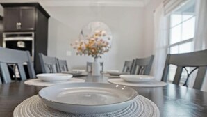 Un tavolo da pranzo con piatti e un vaso di fiori, circondato da sedie.
