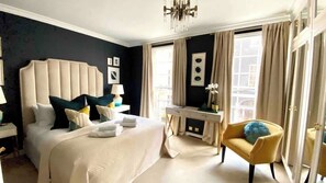 A hotel room with a large bed, a desk, a chair, and a view of the city.