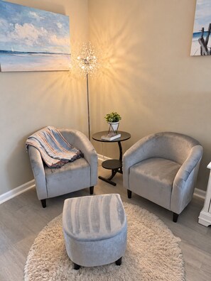 A living room with two armchairs, a round coffee table, a floor lamp, and a rug.