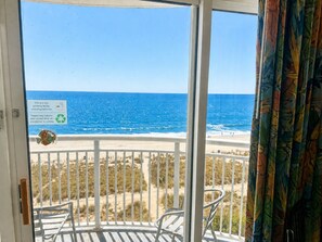 A balcony with a view of the beach and ocean, a sign indicating it's a non-smoking facility, and a recycling symbol.