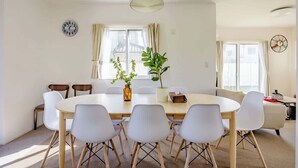 A dining area with a round table, white chairs, and a potted plant. - Luxury Beach Getaway | Pet-Friendly | BBQ, Sauna & Jacuzzi | Up to 9 Guests (Chōsei, Chōsei District)