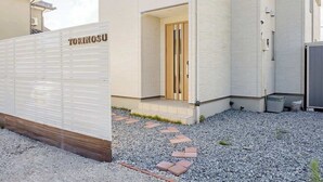 A building with a white exterior and a wooden door labeled "TORINOSU". - Luxury Beach Getaway | Pet-Friendly | BBQ, Sauna & Jacuzzi | Up to 9 Guests (Chōsei, Chōsei District)