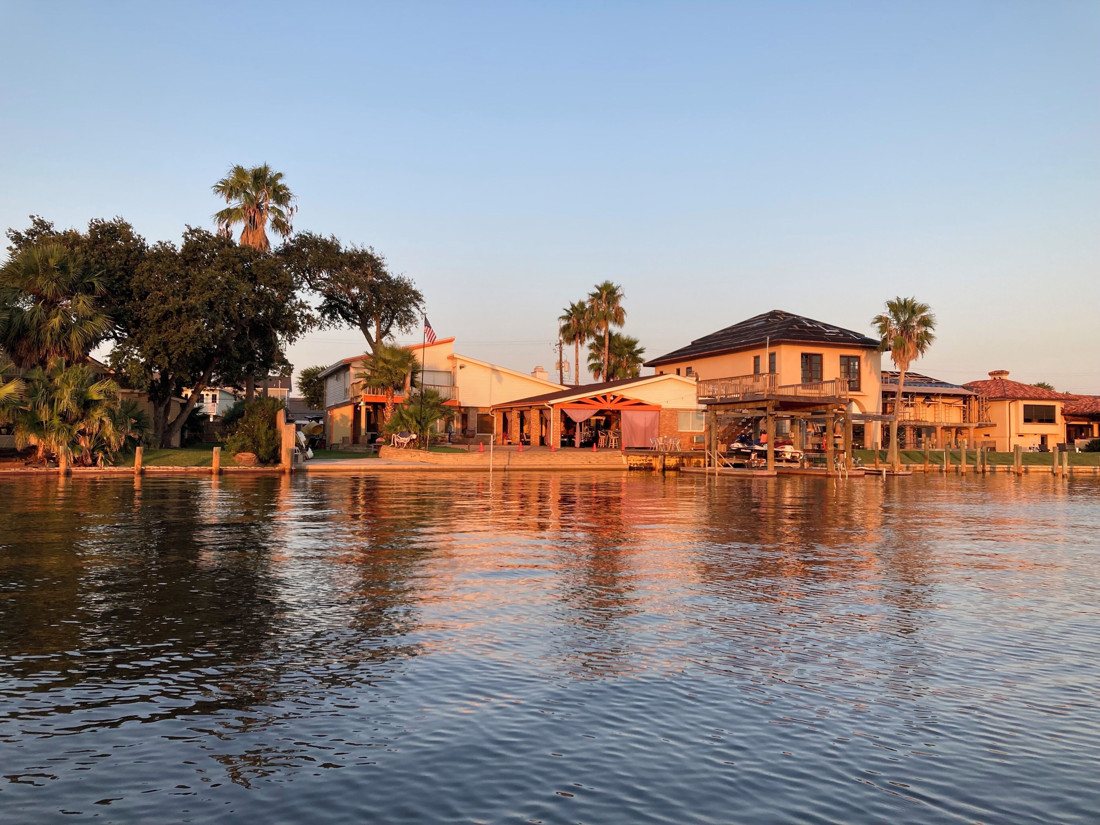 A waterfront property with multiple buildings, including a house with a balcony and a covered patio area.