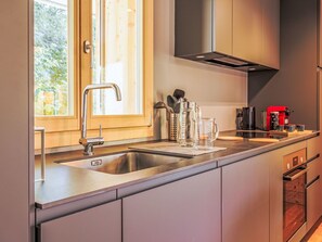 Een koelkast, een oven, een vaatwasser, kookgerei, borden en bestek