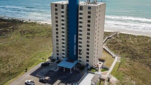 Un grand hôtel, avec une entrée bleue très visible, situé près d’une plage et offrant une vue sur l’océan.