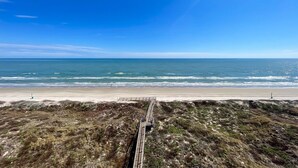 Une plage côtière avec une promenade en bois qui mène au bord de l’eau.