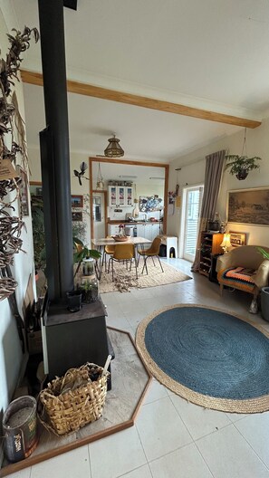 Un salón acogedor con chimenea, un comedor y una cocina al fondo.
