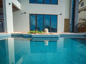 Um edifício moderno com piscina, janelas amplas e uma escultura de pedra.