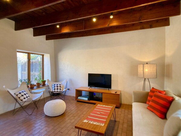 Un salon moderne avec un téléviseur à écran plat, une table basse en bois, un canapé blanc et une lampe.
