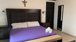 Een netjes opgemaakt bed met een paars sprei, twee kussens en opgerolde handdoeken aan de zijkant.
