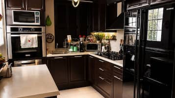 A modern kitchen with dark cabinetry, stainless steel appliances, and a central island.
