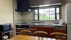 Cocina compacta con microondas, estufa, fregadero y ventana con vistas al exterior.