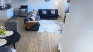 Una sala moderna con un sofá, una mesa de comedor y una cocina al fondo.