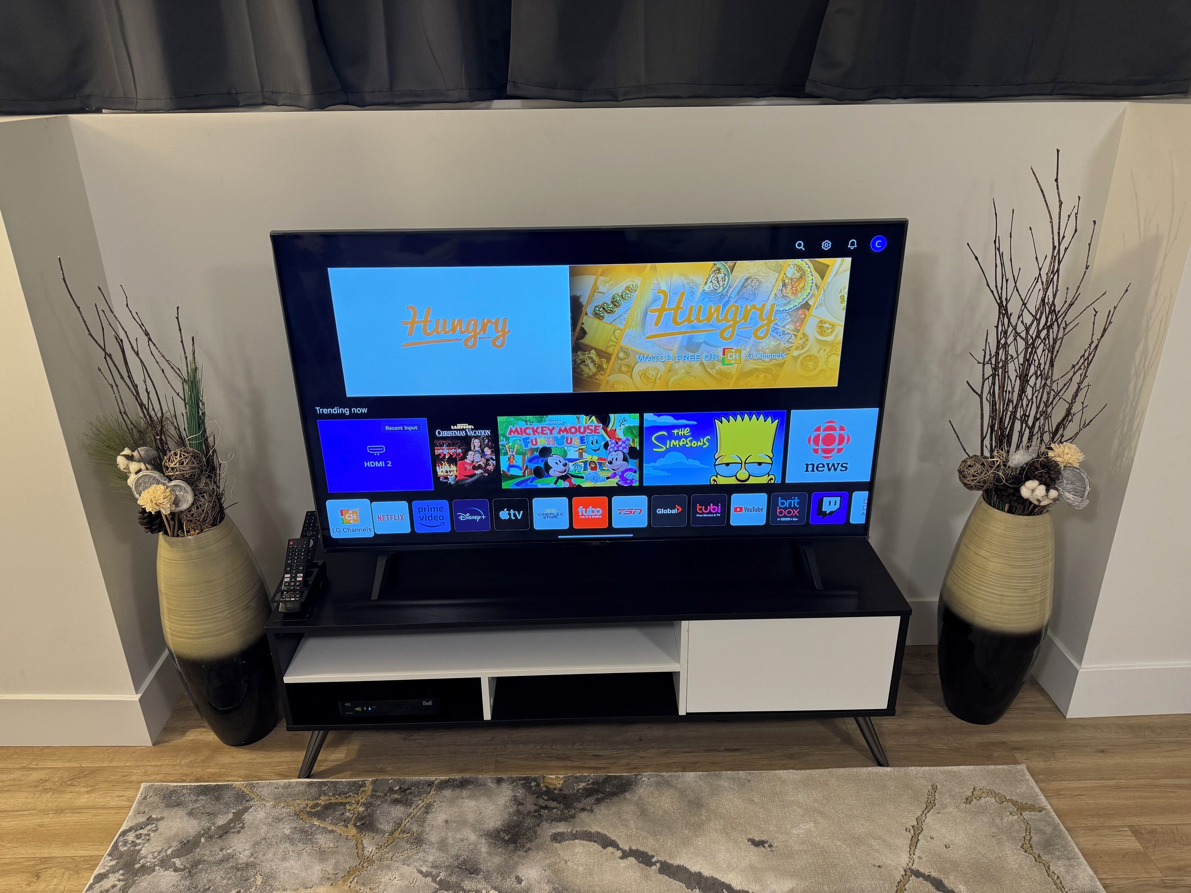 Televisor de pantalla plana montado en la pared, con una selección de servicios de transmisión y una sección 'Lo más visto'.