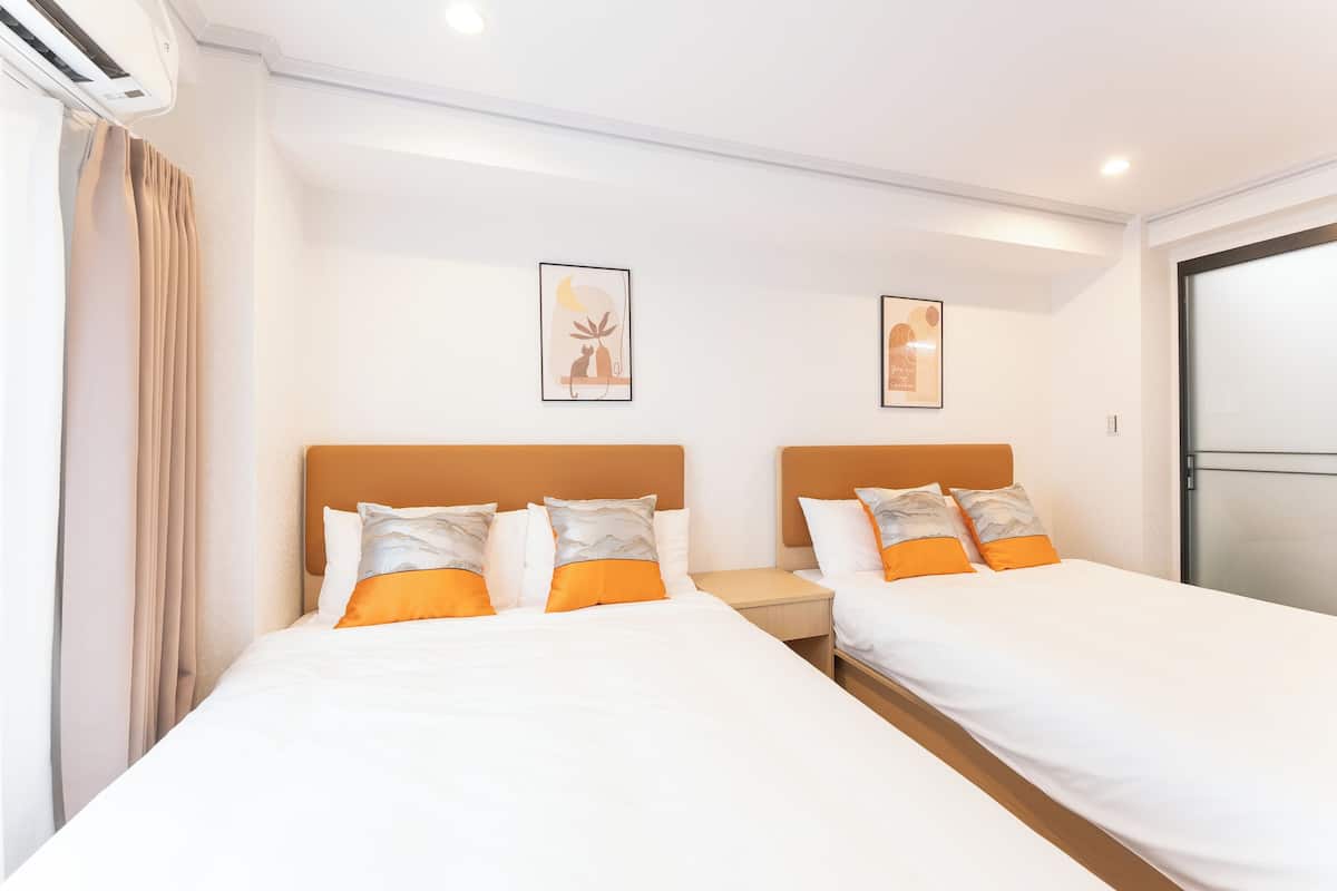 Quarto de hotel com duas camas, cortinas bege e obras de arte emolduradas na parede.