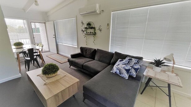 A modern living room with a grey sofa, a wooden coffee table, and a small side table with a lamp. - Esperance Little Units 1 (Castletown)