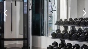 Un gimnasio con una estructura para sentadillas, banco y mancuernas.