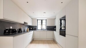 A modern kitchen with white cabinets, a black countertop, and a window providing natural light. - The Covent Garden Maison — 4‑Bed Duplex Sleeps 8 (London)