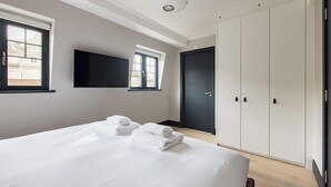 A bedroom with a bed, two windows, a TV, a wardrobe, and a door. - The Covent Garden Maison — 4‑Bed Duplex Sleeps 8 (London)