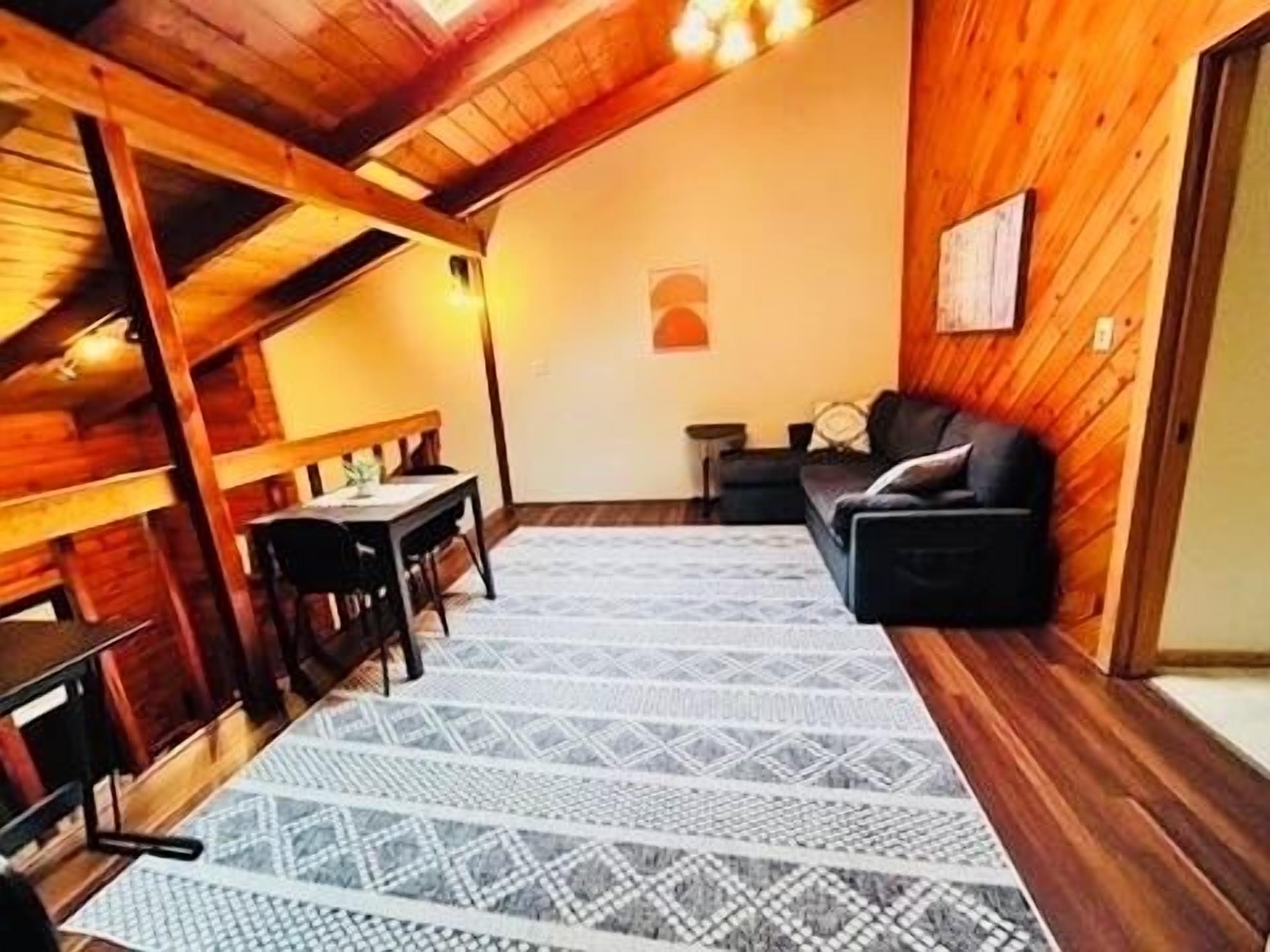 Un interno in legno con una zona pranzo, un divano e un tappeto decorato.