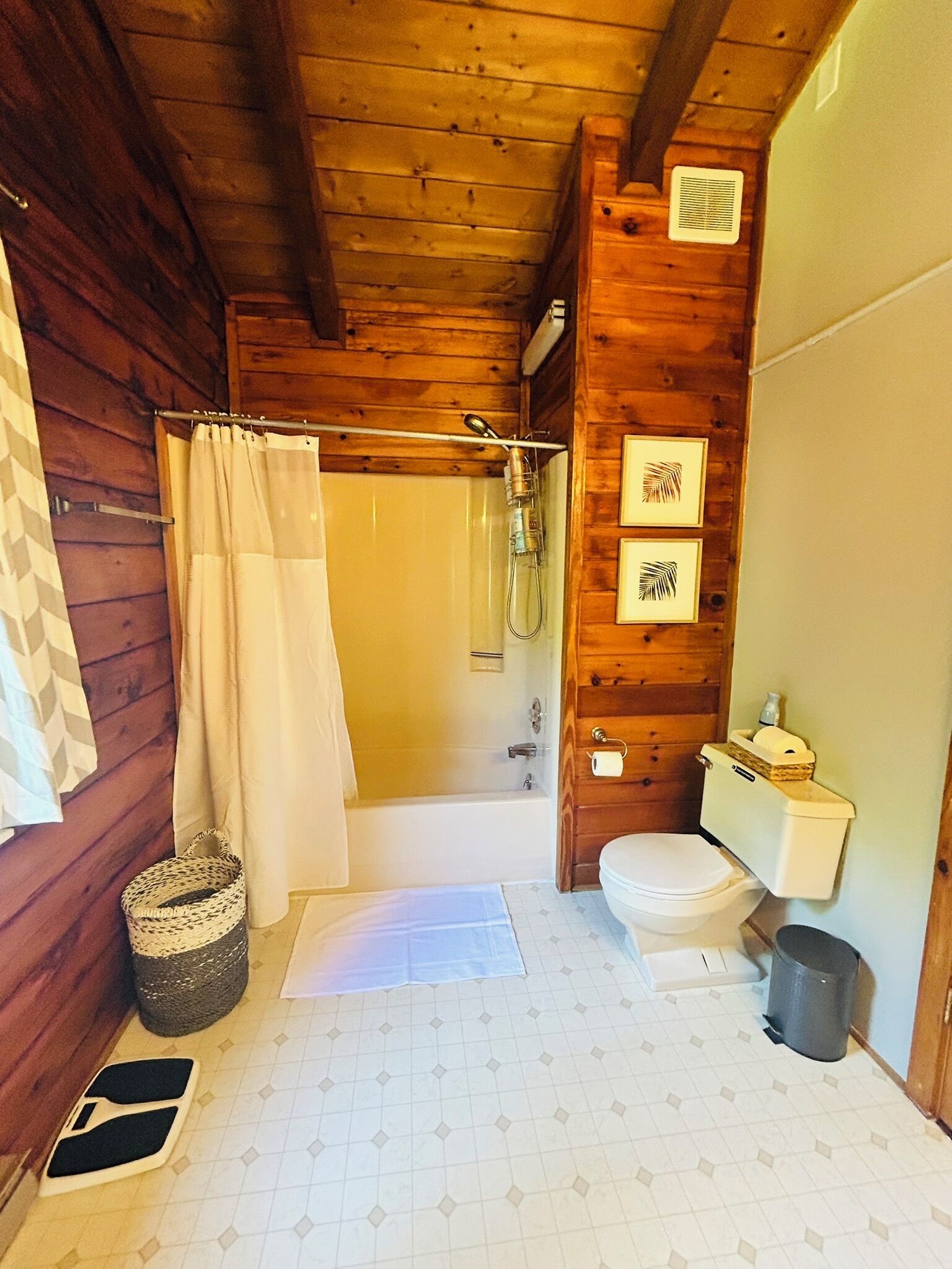 Ein Badezimmer einer Holzhütte mit Dusche, Toilette und einem kleinen Waschbecken.