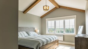 Un dormitorio con una cama de madera, un ventanal grande y un ventilador de techo.