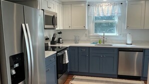 A modern kitchen with stainless steel appliances, white cabinets, and a wooden floor. - 3-Bedroom House in Gorgeous Brewster (Brewster)