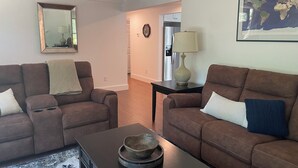 A living room with two brown sofas, a coffee table, a rug, a lamp, and a world map on the wall. - 3-Bedroom House in Gorgeous Brewster (Brewster)
