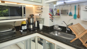 A modern kitchen with a microwave, coffee maker, and various utensils.