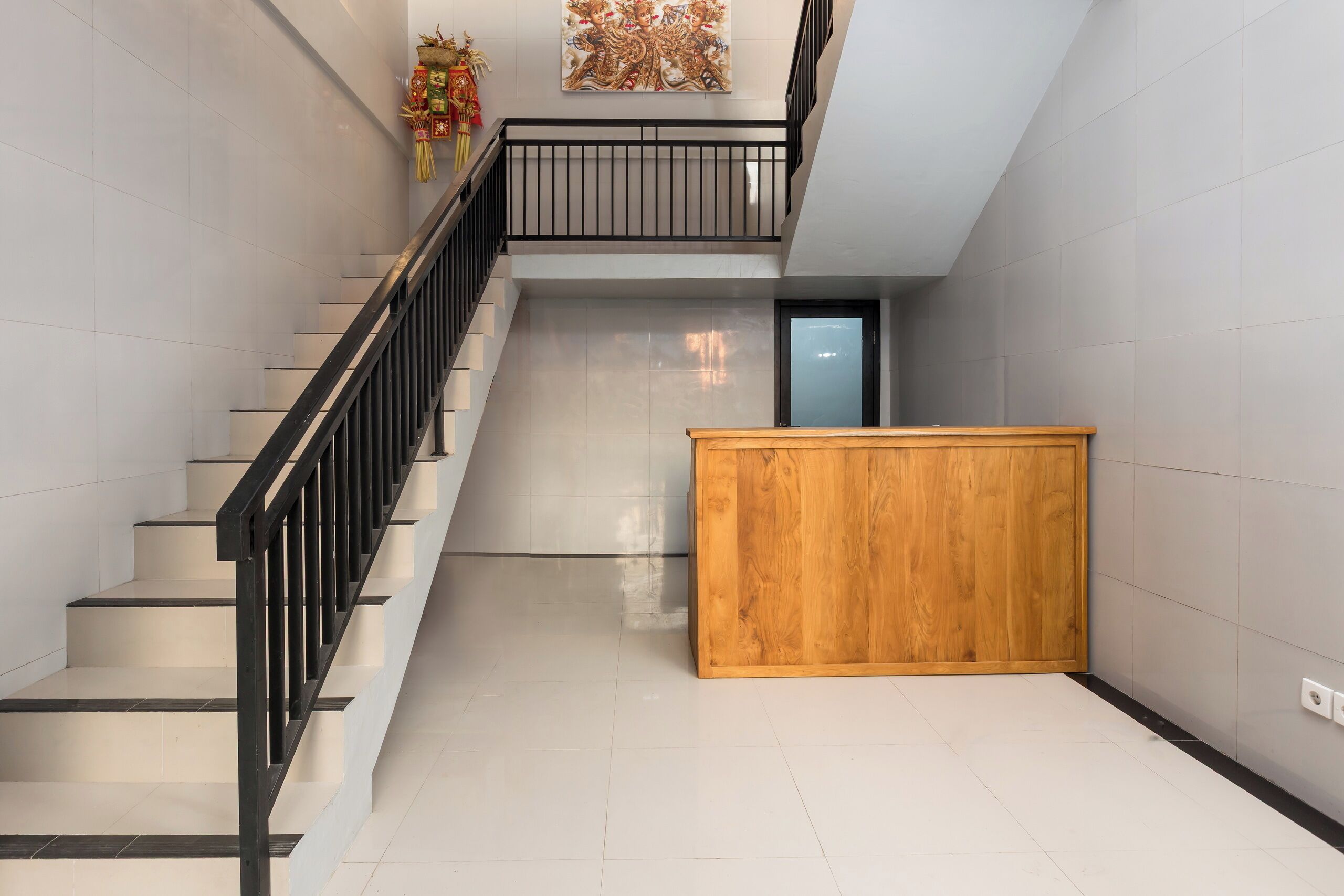 Un interior moderno con una escalera, un banco de madera y un adorno en la pared.