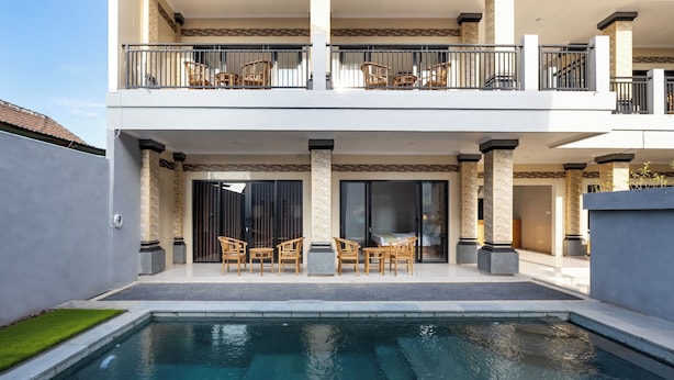 A modern two-story house with a swimming pool, outdoor seating, and a balcony with wicker chairs. - The Tis Guesthouse and Hostel (Canggu)