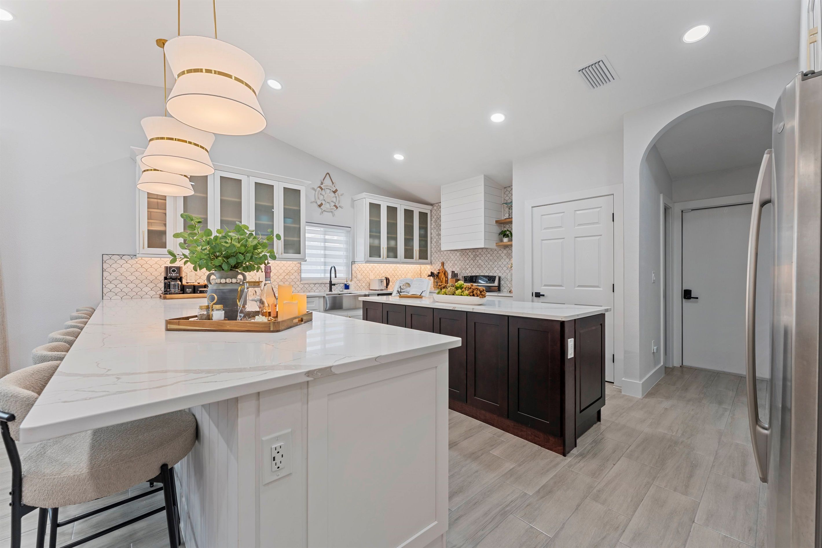 A modern kitchen with a large island, white cabinetry, and pendant lighting.