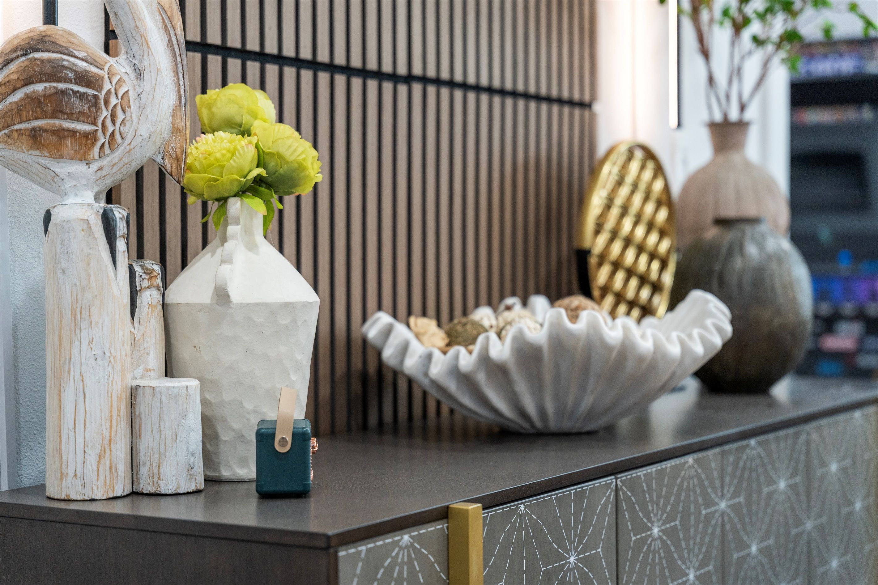 A reception desk with a vase of flowers, a decorative bowl, and a small blue bag.
