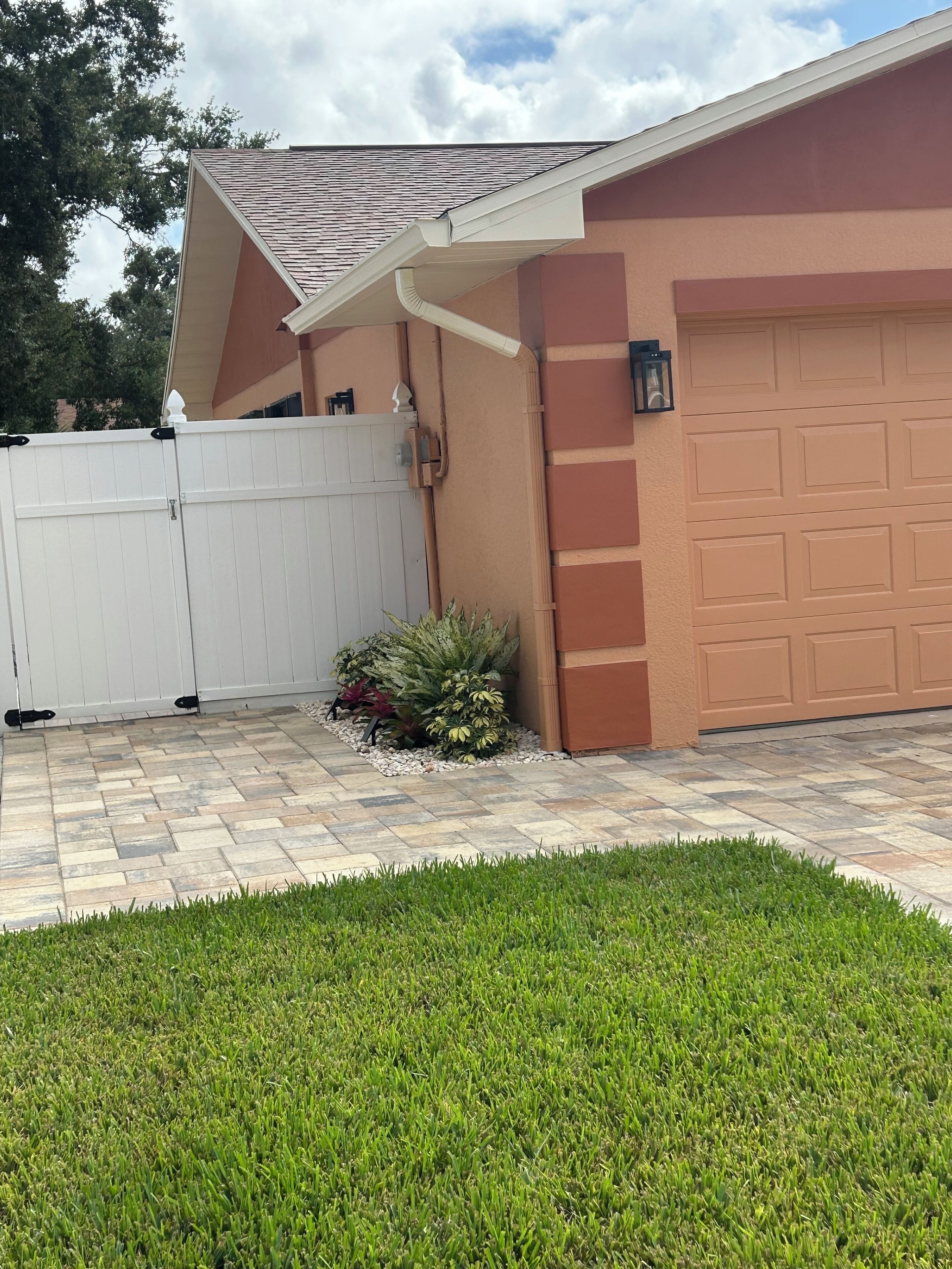 Um imóvel residencial com garagem, cerca branca e jardim ajardinado.