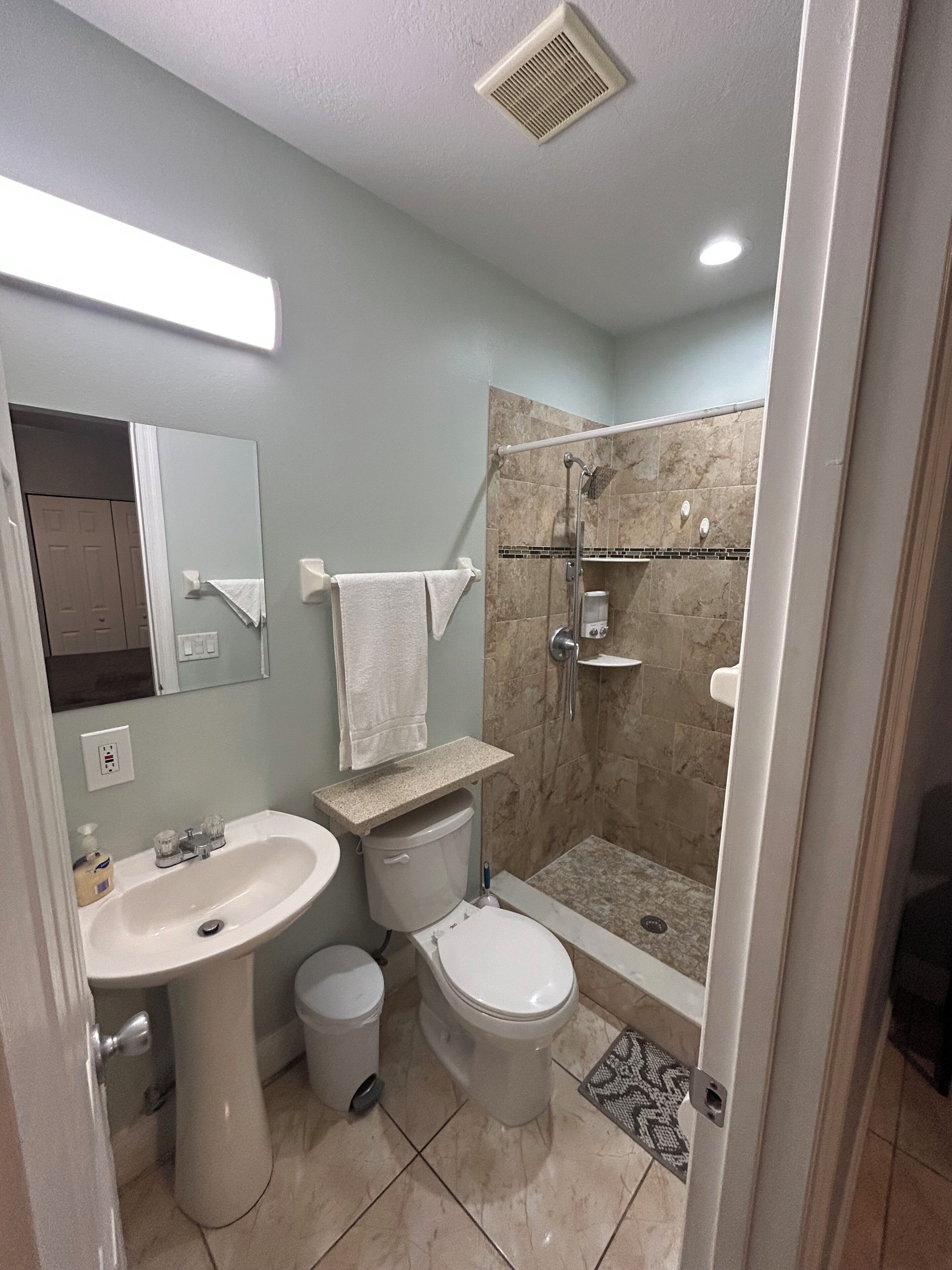 A bathroom with a sink, toilet, and shower.