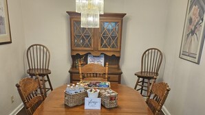 A dining table with chairs, a chandelier, a cabinet with glass doors, and a sign on the cabinet.