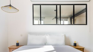 A bedroom with a large bed, two bedside tables, a hanging light fixture, and a large mirror on the wall.