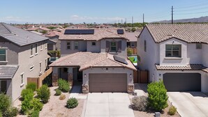A residential area with houses featuring solar panels, a garage, and a well-maintained lawn. - Modern Desert Home–Great for Families & Groups, Near Golf, Hiking & City Fun (Phoenix)