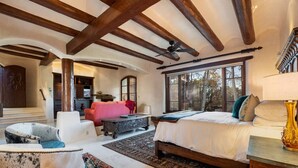 Un dormitorio amplio con una cama grande, un rincón de descanso con sofá y sillones, y vistas al exterior a través de una ventana.
