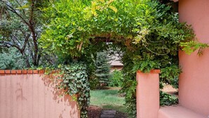 A brick pathway leading to a covered area with a green archway. - Casa de Vida - Huge Yard, Hot Tub (Santa Fe)