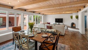 A spacious living area with a fireplace, a TV, and a dining area with a table set for four. - Casa de Vida - Huge Yard, Hot Tub (Santa Fe)
