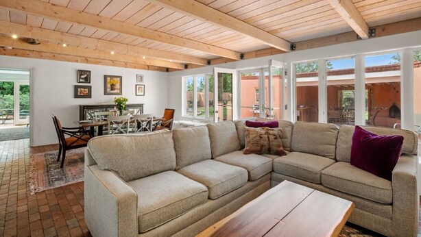 A spacious living room with a sectional sofa, a dining area, and large windows. - Casa de Vida - Huge Yard, Hot Tub (Santa Fe)