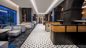 A modern hotel lobby with a geometric patterned floor, seating areas, and a view through large windows. - Guangzhou Elegant International Hotel Panyu Square Metro Station Branch - Free Shuttle Bus to Canton Fair Complex During Canton Fair Period & Free Deliver Service to Guangzhou Baiyun International Airport (Guangzhou)