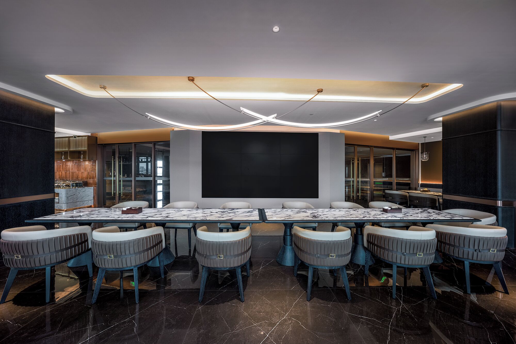 A modern conference room with a large table and chairs, a large screen, and a ceiling with integrated lighting.