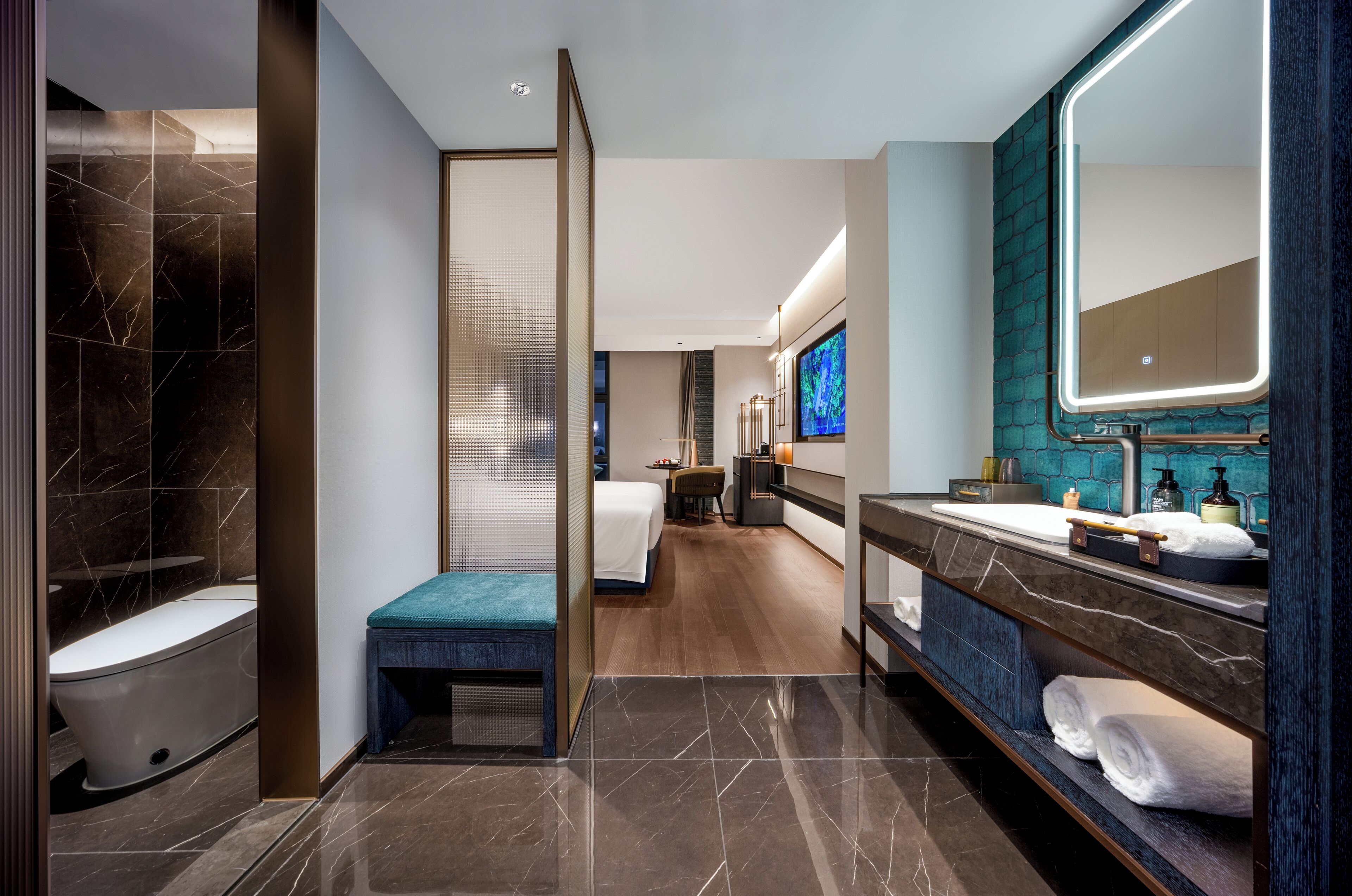 A modern bathroom with a bathtub, a bench, a large mirror, and a vanity with a sink and towel rack.