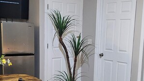 A living room with a dining area, a TV mounted on the wall, and two white doors. - ♥ Stunning 3BR Newark Retreat ★ Parking & Near NYC & EWR Airport (Newark)